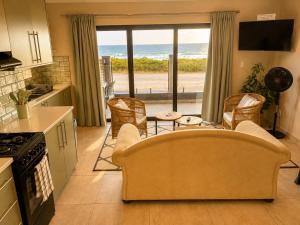 a living room with a couch and a kitchen with a view at White Sands Self-catering units in Wilderness