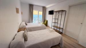 a hotel room with three beds and a window at Albergue EL CASTILLO in Sarria