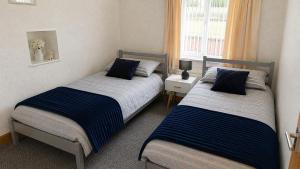 two beds in a small room with a window at Coed Bach Suite in Bryngwran