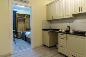 a kitchen with white cabinets and a room with a bed at Grand 464 Otel in Rize