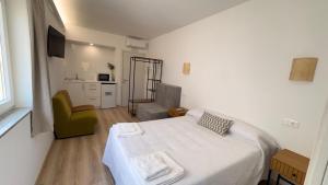 a white bedroom with a bed and a chair at Albergue EL CASTILLO in Sarria