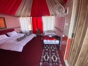 a bedroom with two beds in a room with red curtains at Salem Wadi Rum Road in Wadi Rum
