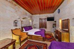 ein Schlafzimmer mit einem Bett, einem Tisch und einem Fernseher in der Unterkunft Hidden Cave Hotel in Goreme
