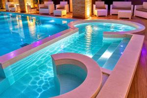 a swimming pool in a hotel with white chairs at La Corte di Leuca Residence in Leuca