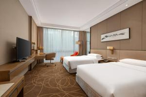 a hotel room with two beds and a flat screen tv at Greenland Mansion in Shanghai