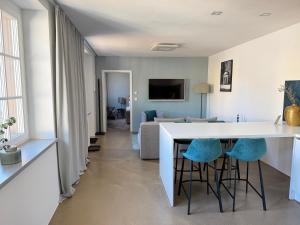 a kitchen and living room with a white counter and stools at Rotmain Apartments in Bayreuth
