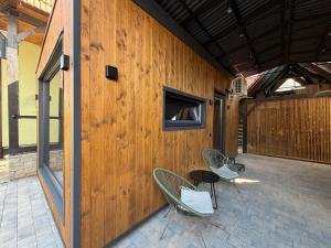 a patio with two chairs and a window on a wooden wall at U Dominicana in Kamianets-Podilskyi