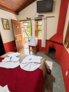 a room with a bed with a tv on the wall at Pousada Toque de Minas in Visconde De Maua