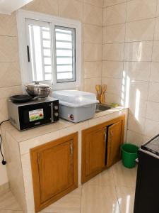 a kitchen with a microwave and a sink and a window at Villa Daoura in Niamey