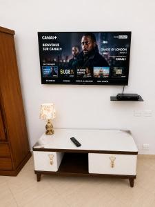 a tv hanging on a wall with a white table at Villa Daoura in Niamey +5 photos