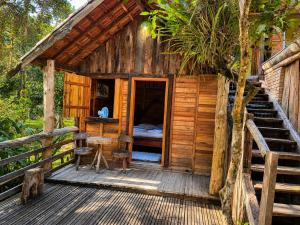 a cabin with a bed and a wooden deck at Pousada Toque de Minas in Visconde De Maua