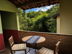 a table and two chairs on a porch with a window at Pousada Toque de Minas in Visconde De Maua