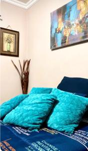 a bed with blue sheets and a painting on the wall at SummerPlace Studio Apartments with Kitchenette in Modimolle