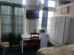 a bedroom with a desk and a refrigerator and a bed at Camp Inn Lodge in Pietermaritzburg