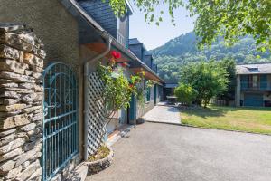 a stone building with a gate with flowers on it at Gîte de groupe Le Domaine - 26 personnes au coeur des Pyrénées l Ô Domaine de Geu in Geu