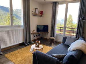 a living room with a blue couch and large windows at Résidence les 3 Sommets in Sarcenas
