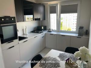 a kitchen with white cabinets and a table with a television at Rubinkowo Rooms Self Check-in 24h in Toruń