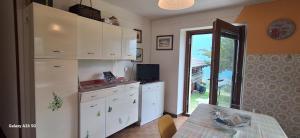 a kitchen with white cabinets and a table and a window at Il Melo in Trasquera +14 photos