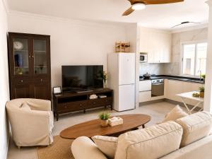 a living room with a white refrigerator and a table at Roca Playa Mogan in Puerto de Mogán