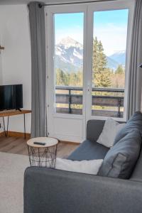 a living room with a couch and a large window at Résidence les 3 Sommets in Sarcenas