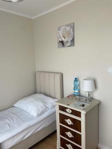 a bedroom with a bed and a dresser with a lamp at Rubinkowo Rooms Self Check-in 24h in Toruń