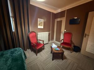 a hotel room with two chairs and a bed and a table at Les 3 rois by YY in Villers-Bocage
