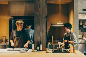 two men standing in a kitchen preparing food at VILLA COMMUNICO,Nara in Nara