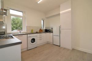 a kitchen with white cabinets and a washer and dryer at Macintosh lower in Bellshill +8 photos