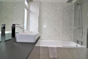 a white bathroom with a sink and a shower at Macintosh lower in Bellshill