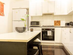 a kitchen with white cabinets and a counter top at Secluded Hackney Cottage Near Botanic Gardens with Free Parking - Koala Stay in Adelaide +12 photos