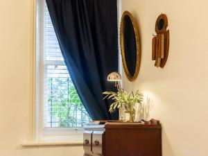 a window with a blue curtain and a table with a plant at Secluded Hackney Cottage Near Botanic Gardens with Free Parking - Koala Stay in Adelaide