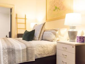 a bedroom with a bed with a lamp and pillows at Secluded Hackney Cottage Near Botanic Gardens with Free Parking - Koala Stay in Adelaide