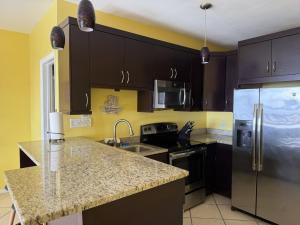 a kitchen with black cabinets and a stainless steel refrigerator at Charming 1BR Villa Steps from Red Hook Hotspots in Nazareth