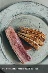 a plate with a piece of meat and some bread at VILLA COMMUNICO,Nara in Nara