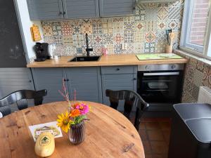 a kitchen with a wooden table with a vase of flowers on it at Suzie's Cottage in Aalten