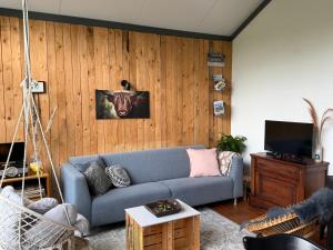 a living room with a blue couch and wooden walls at Suzie's Cottage in Aalten