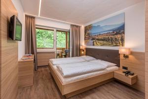 a bedroom with a bed with a painting on the wall at Pension Irma in Caldaro