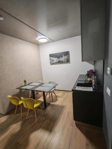 a kitchen with a table and yellow chairs in a room at Jáde Residence Apartman in Sárvár