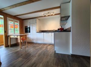 a kitchen with white cabinets and a wooden floor at Chalet Sonnenheim mit atemberaubender Aussicht in Adelboden