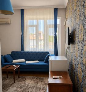 a living room with a blue couch in front of a window at Green Moringa Termal Hotel in Termal