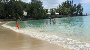 a group of people standing in the water on a beach at Blue Haven in Grand-Baie