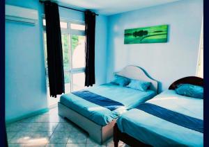 a blue room with two beds and a window at Blue Haven in Grand-Baie