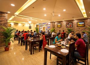 a group of people sitting at tables in a restaurant at Hotel Grand Suites Premier - Near Delhi Aerocity in New Delhi