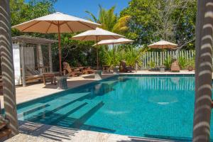 a swimming pool with two umbrellas and chairs at Village Mata Encantada in Santo André