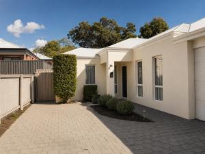 a white house with a fence and a driveway at Layover Lounge in Perth