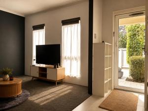 a living room with a flat screen tv and a door at Layover Lounge in Perth