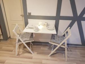 a white table and two chairs with cups and saucers at klein aber fein in Freudenthal