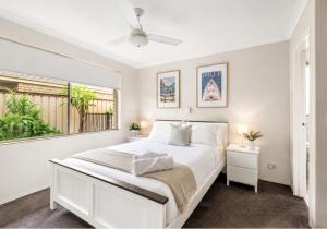 a white bedroom with a bed and a window at Canal escape with private jetty and huge deck in South Yunderup