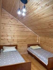 two beds in a room with wooden walls at Adam in Chon-Sary-Oy