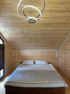 a bed in a wooden room with a chandelier at Adam in Chon-Sary-Oy